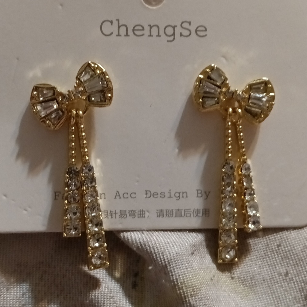 Gold tone bow diamond dangling earrings